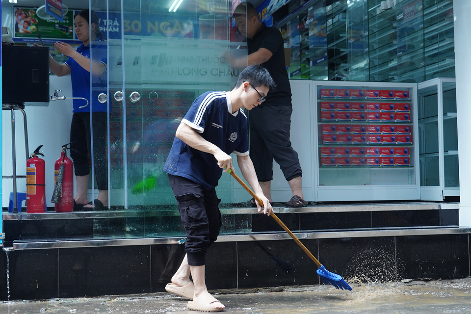 Người dân dùng chổi, cọ, liên tục khuấy để nước bùn không đọng lại trong nhà cửa. (Ảnh: Việt Anh/Vietnam+)