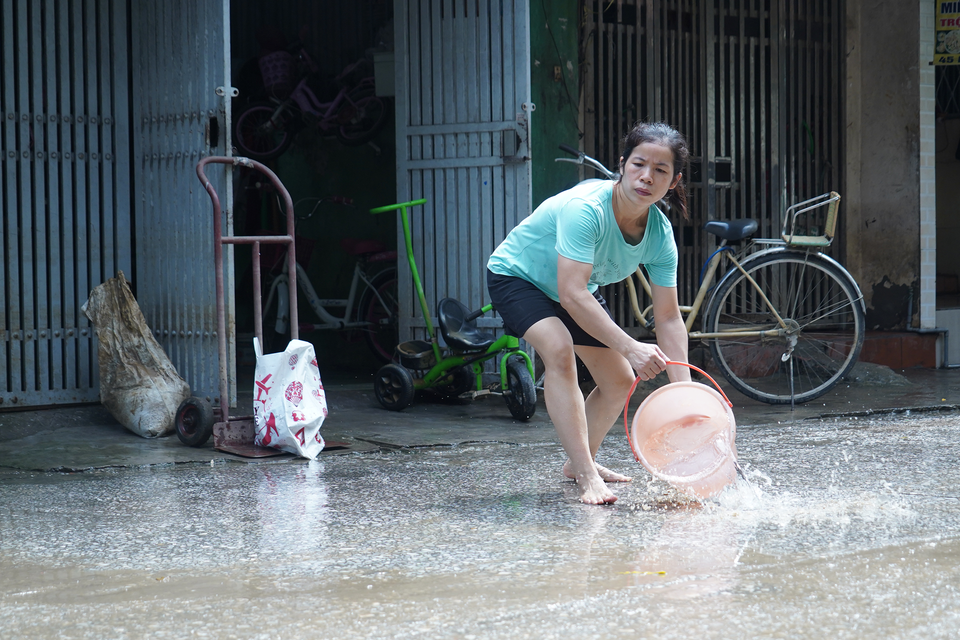 Các xô, chậu cũng được mang ra hứng nước, rửa sạch nền đường. (Ảnh: Việt Anh/Vietnam+)