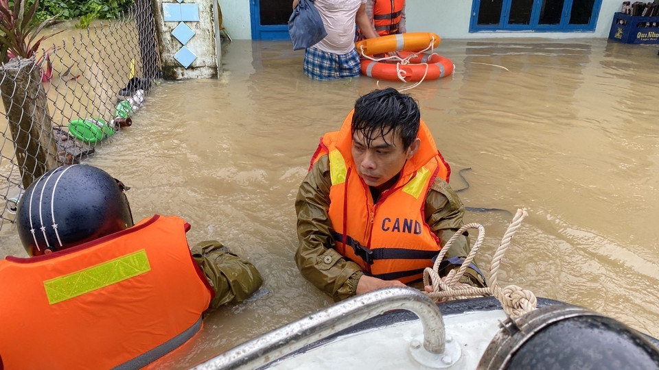Công an huyện Tuy Phước dầm mình trong nước lũ hỗ trợ di chuyển người dân. (Ảnh: Tường Quân/TTXVN)