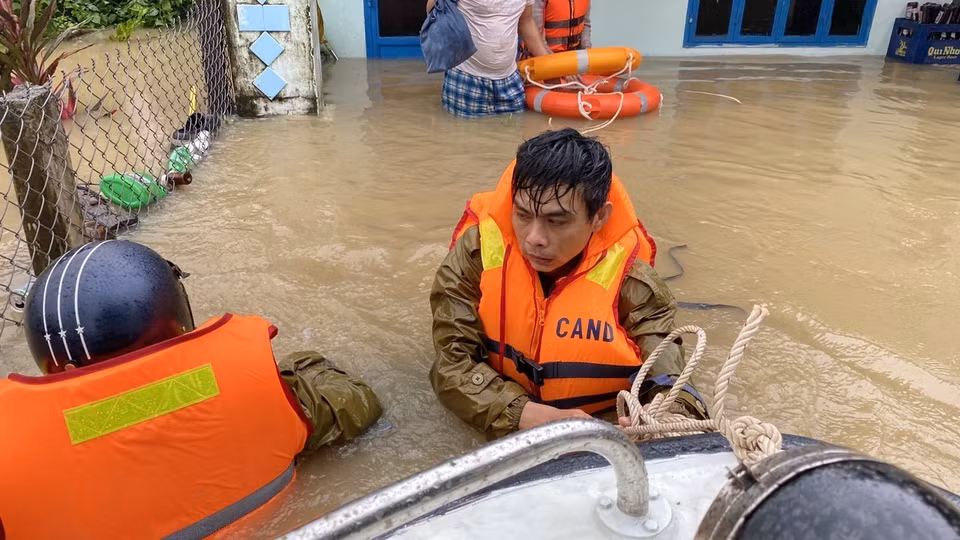 Công an huyện Tuy Phước dầm mình trong nước lũ hỗ trợ di chuyển người dân. (Ảnh: Tường Quân/TTXVN)