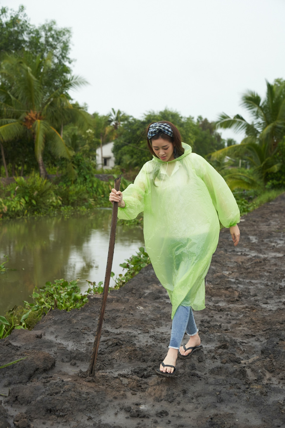 Đoàn bất ngờ gặp cơn mưa lớn khi đang trên đường di chuyển tới địa điểm, nhưng Hoa hậu Khánh Vân và mọi người vẫn mặc áo mưa, vượt quãng đường bộ sình lầy gần 2km để đến nhà người dân. (Ảnh: Sang Đào/Vietnam+)