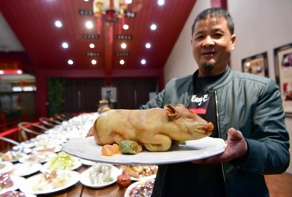 Nghệ nhân điêu khắc đá Sun Zhaoyong giới thiệu món ăn Lợn sữa quay bằng đá tại triển lãm đá ở Phúc Châu, Trung Quốc ngày 1/2. (Ảnh: THX/TTXVN)
