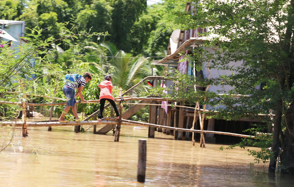 Nhiều em phải băng qua cây cầu khỉ khá dài mới vào được nhà. (Ảnh: Công Mạo/TTXVN)