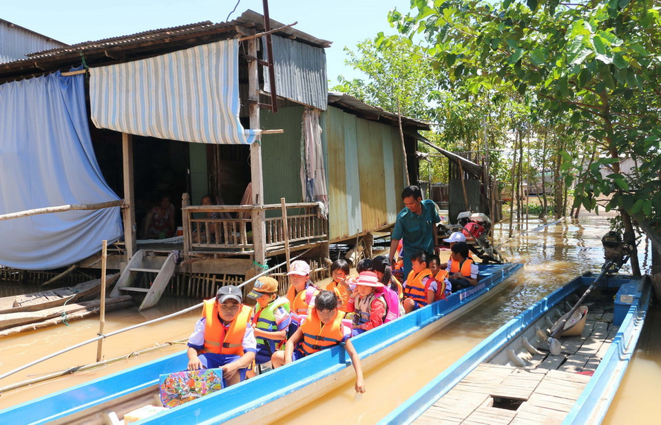 Các em học sinh Trường Tiểu học B Vĩnh Hội Đông ở 2 ấp Vĩnh Hòa và Vĩnh An sau khi tan học được anh Trần Văn Hiền - chiến sỹ dân quân tự vệ xã Vĩnh Hội Đông lái vỏ lãi (xuồng) đưa về tận nhà. (Ảnh: Công Mạo/TTXVN)