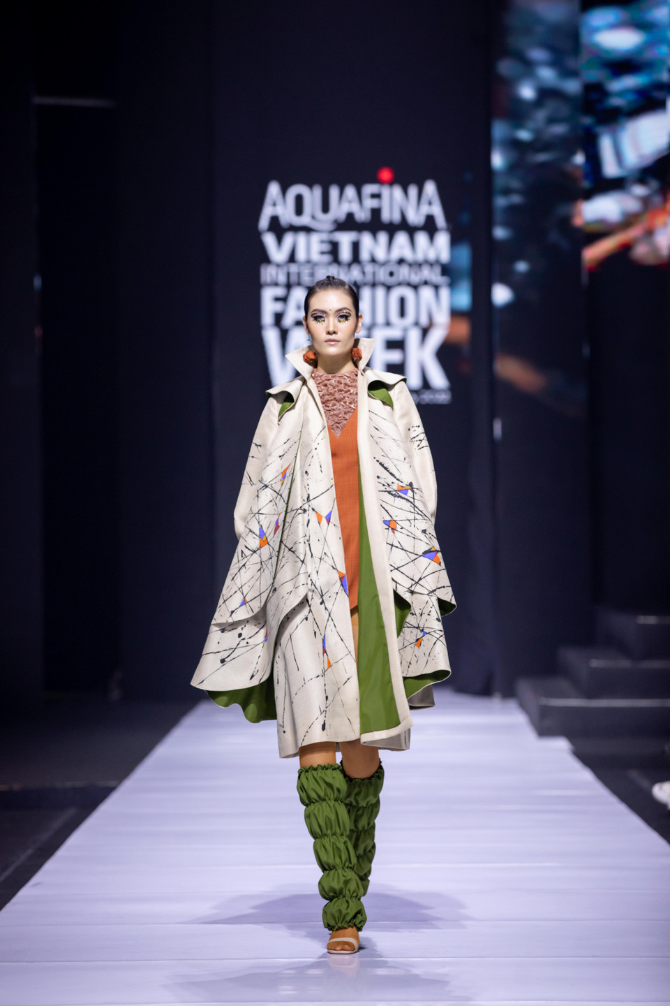 Đảm nhận vị trí mở màn cho show diễn là Quán quân The Next Face 2021 Y Hạ. Y Hạ xuất hiện cuốn hút và bước đi uyển chuyển trong bộ jumpsuit màu cam neon bắt mắt, phối cùng blazer dáng dài có thiết kế độc đáo. (Ảnh: CTV/Vietnam+)