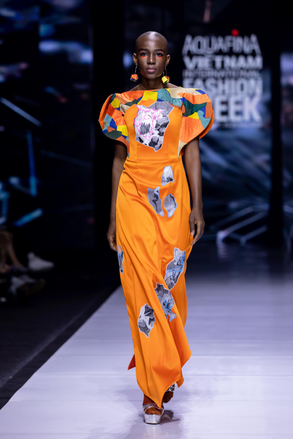 Tiny Ink by Hoàng Quyên tận dụng màu cam neon đại diện cho đất, màu xanh cyan đại diện cho những viên ngọc quý làm gam màu chủ đạo, kết hợp khéo léo các họa tiết vẽ tay thủ công mang dấu ấn thương hiệu nhằm truyền tải sâu sắc thông điệp của bộ sưu tập. (Ảnh: CTV/Vietnam+)