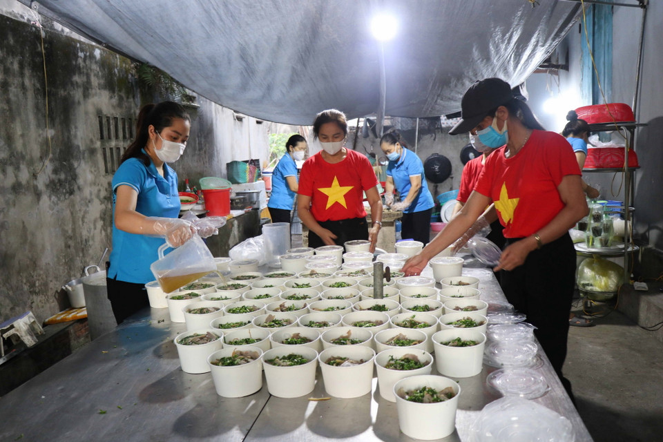 Chị em phụ nữ huyện Gia Bình chuẩn bị suất ăn cho lực lượng tuyến đầu chống dịch. (Ảnh: Thanh Thương/TTXVN)