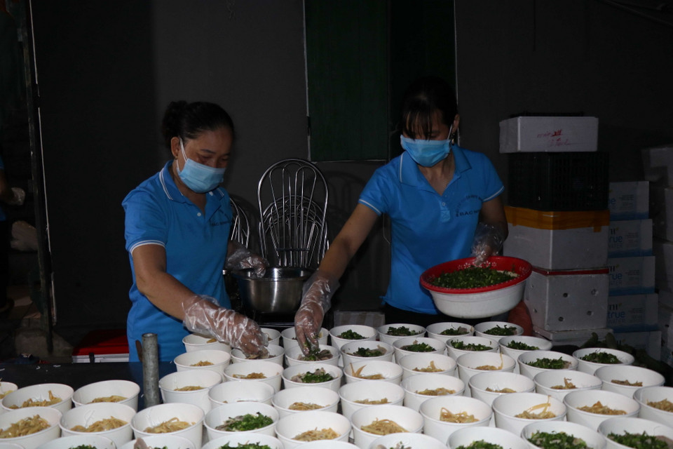 Chị em phụ nữ huyện Gia Bình chuẩn bị suất ăn cho lực lượng tuyến đầu chống dịch. (Ảnh: Thanh Thương/TTXVN)