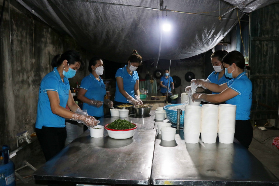Chị em phụ nữ huyện Gia Bình chuẩn bị suất ăn cho lực lượng tuyến đầu chống dịch. (Ảnh: Thanh Thương/TTXVN)