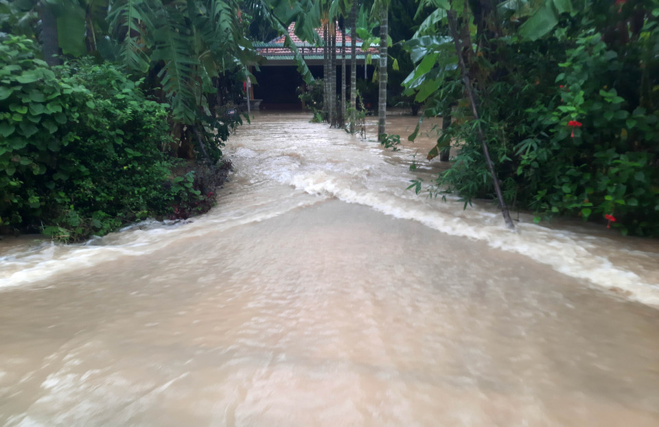 Nước lũ từ sông Hiếu tràn qua đường giao thông tại xã Cam Thủy, huyện Cam Lộ. (Ảnh: Hồ Cầu/TTXVN)