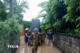 Lực lượng chức năng hỗ trợ người dân di chuyển tài sản đến nơi an toàn. (Ảnh: Đồng Thúy/TTXVN)