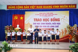 Các học sinh nghèo, hiếu học tại xã Long Chữ, tỉnh Tây Ninh nhận học bổng từ Phó Thủ tướng Chính phủ Lê Tiến Châu (phải) và Chủ tịch UBND tỉnh Tây Ninh Lê Văn Hẳn (trái). (Ảnh: Giang Phương/TTXVN)