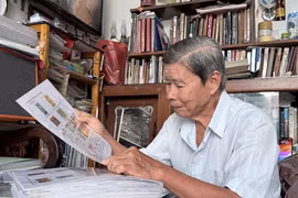 Ông Trần Hữu Huệ xem bì thư dán tem về Hoàng Sa được gửi từ nước ngoài, một hiện vật quý trong bộ sưu tập tem về chủ quyền biển, đảo Việt Nam. (Ảnh: Thanh Sang/TTXVN)