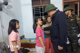 Phó Thủ tướng Thường trực Nguyễn Hòa Bình động viên các cháu học sinh được các lực lượng ứng cứu từ vùng ngập sâu. (Ảnh: Tuấn Anh/TTXVN)