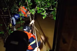 Lực lượng chức năng đu dây ra giữa dòng kênh để cứu người. (Ảnh: TTXVN phát)