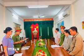 Cơ quan cảnh sát điều tra tống đạt các quyết định tố tụng đối với Trần Mỹ Tiên (áo carô). (Ảnh: TTXVN phát)