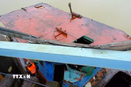 Một phần của xà lan lớn đang mắc kẹt vào thành cầu đường sắt Mỹ Chánh. (Ảnh: Thanh Thủy/TTXVN)