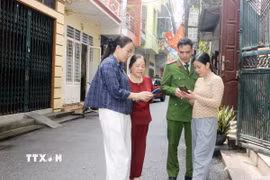 Tổ công nghệ số cộng đồng cùng cán bộ công an phường Phủ Lý, tỉnh Ninh Bình đến từng khu dân cư hướng dẫn người dân tham gia góp ý dự thảo các văn kiện Đại hội XIV của Đảng thông qua ứng dụng VNeID. (Ảnh: Nguyễn Chinh/TTXVN)