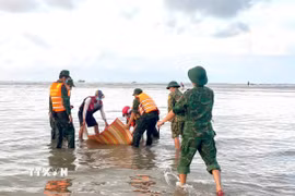 Lực lượng Đồn Biên phòng Tân Thành cùng người dân đưa thi thể du khách bị đuối nước tại khu vực biển Kê Gà (Lâm Đồng) lên bờ. (Ảnh: TTXVN phát)