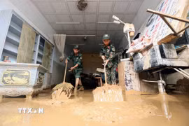 Lực lượng quân đội hỗ trợ người dân tổ 4, xã Sông Mã thu gom bùn đất, cành cây, rác bị tràn về trong đợt lũ vừa qua. (Ảnh: Quang Quyết/TTXVN)