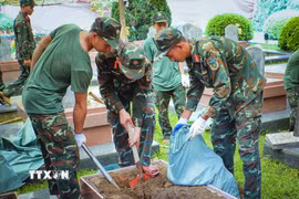 Lực lượng tham gia dùng xẻng và các dụng cụ chuyên dụng để khai quật phần mộ liệt sỹ. (Ảnh: Xuân Tư/TTXVN)