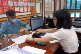 Cán bộ Trung tâm phục vụ hành chính công phường Kim Bảng hướng dẫn người dân làm thủ tục hành chính. (Ảnh: Nguyễn Chinh/TTXVN)