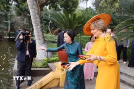 Bà Nguyễn Thị Minh Nguyệt, Phu nhân Chủ tịch nước và Hoàng hậu Vương quốc Bỉ Mathilde cho cá ăn tại ao cá Bác Hồ, Khu Di tích Chủ tịch Hồ Chí Minh. (Ảnh: An Đăng/TTXVN)