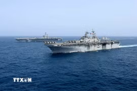 Tàu sân bay USS Abraham Lincoln (phía sau) của hải quân Mỹ di chuyển trên Biển Arab. (Ảnh minh họa: AP/TTXVN)