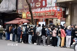 Người dân xếp hàng dài chờ mua vàng tại cửa hàng Bảo Tín Minh Châu trên phố Trần Nhân Tông, Hà Nội, dù có thông báo tạm hết hàng. (Ảnh: Trần Việt/TTXVN)