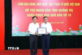 Ông Trần Cẩm Tú, Ủy viên Bộ Chính trị, Thường trực Ban Bí thư thay mặt lãnh đạo Đảng, Nhà nước trao kinh phí hỗ trợ nhân dân tỉnh Quảng Trị. (Ảnh: Phương Hoa/TTXVN)