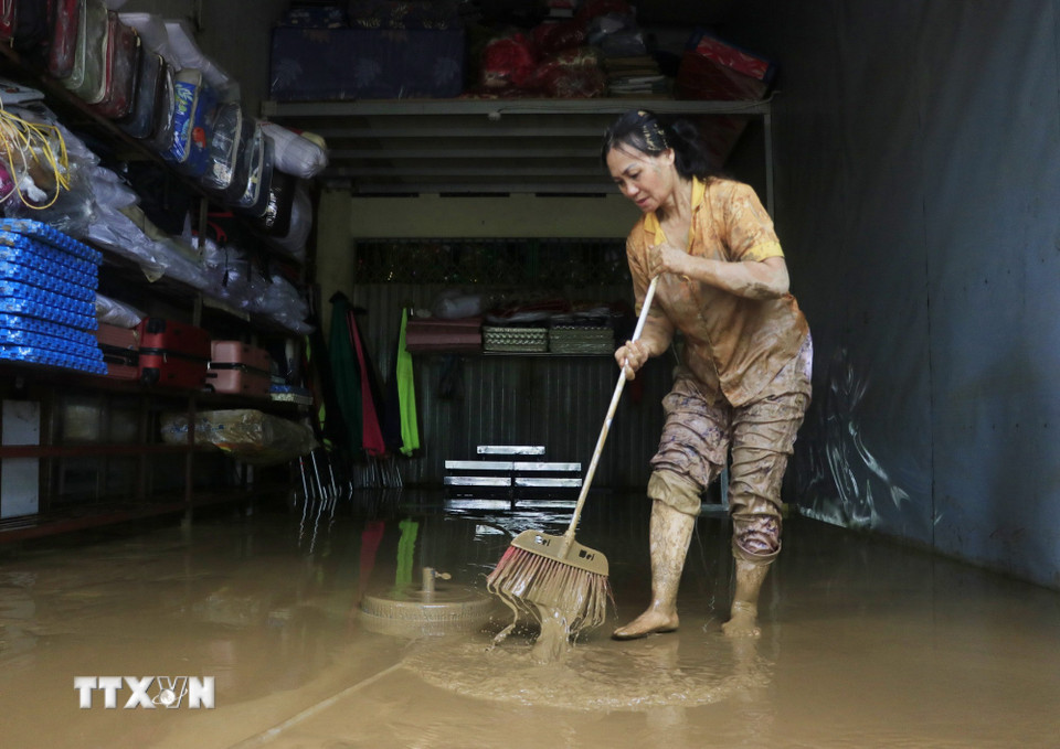 Người dân phường Yên Bái, tỉnh Lào Cai dọn dẹp nhà cửa sau khi nước rút. (Ảnh: Đinh Thùy/TTXVN)
