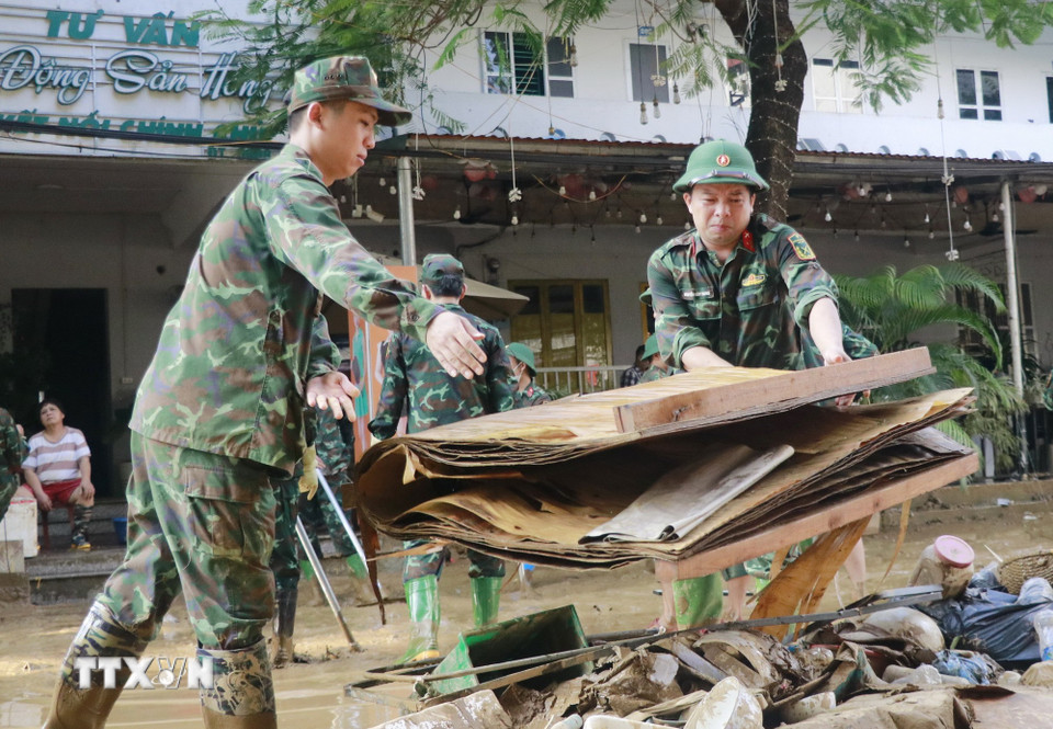 Cán bộ, chiến sỹ Bộ Chỉ huy Quân sự tỉnh Lào Cai giúp dân dọn dẹp bùn đất trên đường phố. (Ảnh: Đinh Thùy/TTXVN)