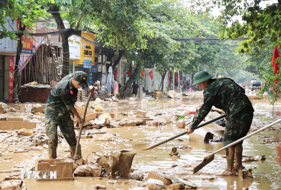 Cán bộ, chiến sỹ Bộ Chỉ huy Quân sự tỉnh Lào Cai giúp dân dọn dẹp bùn đất trên đường phố. (Ảnh: Đinh Thùy/TTXVN)