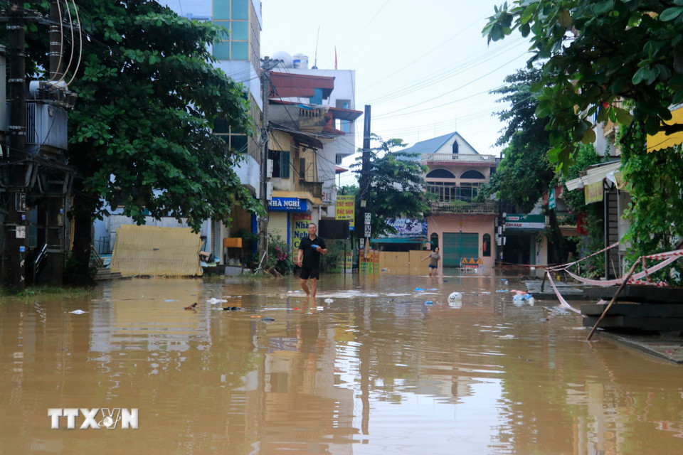 Việc đi lại của người dân Lào Cai ở các khu vực bị ngập gặp khó khăn do nước sông Hồng rút chậm. (Ảnh: Đinh Thùy/TTXVN)