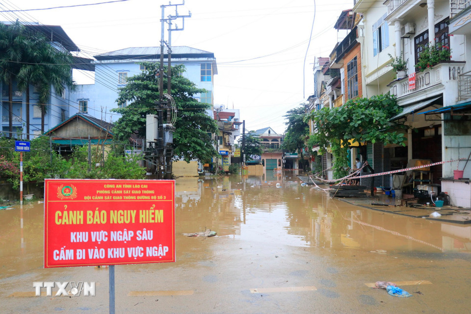 Lực lượng chức năng Lào Cai căng dây và cắm biển cảnh báo các khu vực ngập. (Ảnh: Đinh Thùy/TTXVN)