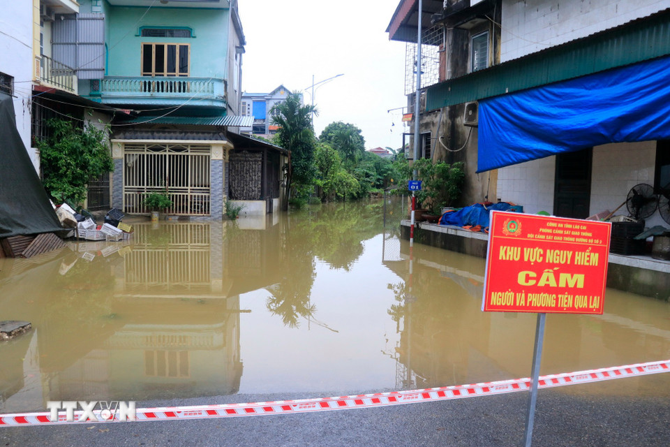 Lực lượng chức năng căng dây và cắm biển cảnh báo các khu vực ngập ở Lào Cai. (Ảnh: Đinh Thùy/TTXVN)