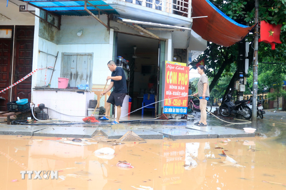 Bà con nhân dân phường Yên Bái, Lào Cai tranh thủ dọn dẹp trong nhà khi nước rút. (Ảnh: Đinh Thùy/TTXVN)