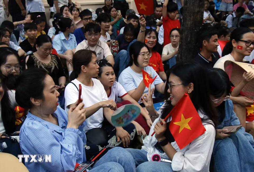 Nhiều bạn trẻ tranh thủ “check-in” cùng cờ Tổ quốc trong khi chờ đợi diễu binh, diễu hành. (Ảnh: Tiến Lực/TTXVN)