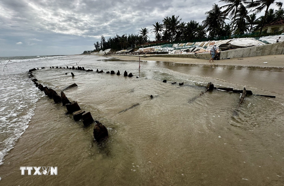 Con tàu gỗ ẩn hiện trong sóng và cát biển. (Ảnh: Trần Lê Lâm/TTXVN)