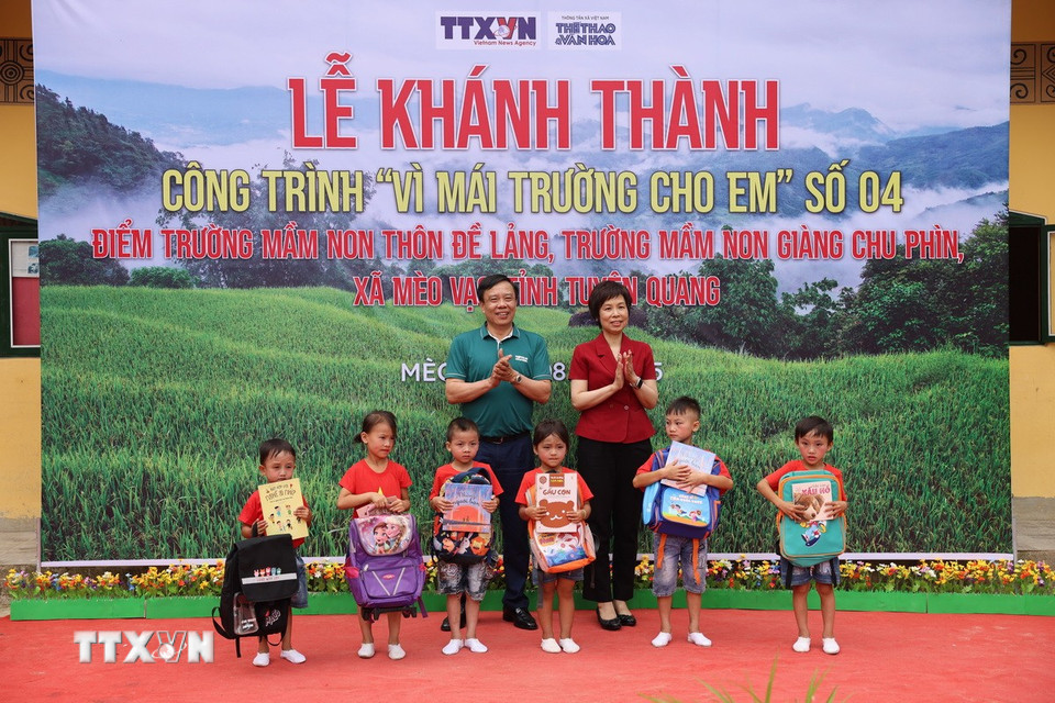 Nhà báo Vũ Việt Trang, Bí thư Đảng ủy, Tổng Giám đốc TTXVN và nhà báo Nguyễn Thiện Thuật, Tổng biên tập Báo Thể thao và Văn hóa tặng quà cho các em Trường Mầm non Đề Lảng. (Ảnh: Huy Thông/TTXVN)