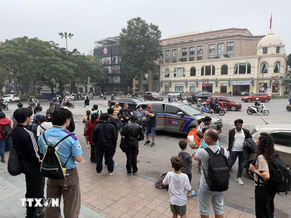 Xe taxi trả khách du lịch trước Nhà hát Lớn - Quảng trường Cách mạng tháng Tám để trung chuyển đi tiếp bằng xe trên 16 chỗ. (Ảnh: Tú Anh/TTXVN phát)