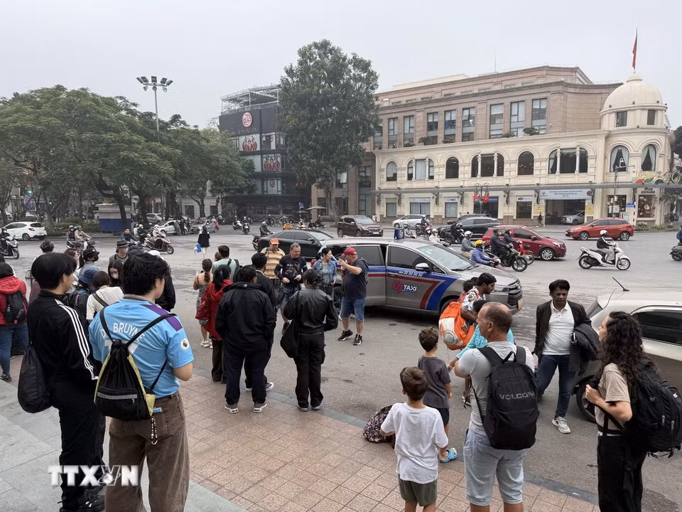 Xe taxi trả khách du lịch trước Nhà hát Lớn - Quảng trường Cách mạng tháng Tám để trung chuyển đi tiếp bằng xe trên 16 chỗ. (Ảnh: Tú Anh/TTXVN phát)
