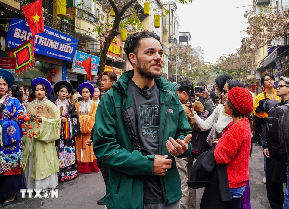 Một du khách nước ngoài thích thú chia sẻ những cảm xúc của mình khi thấy những bộ cổ phục Việt trên phố cổ Hà Nội. (Ảnh: Khánh Hòa/TTXVN)