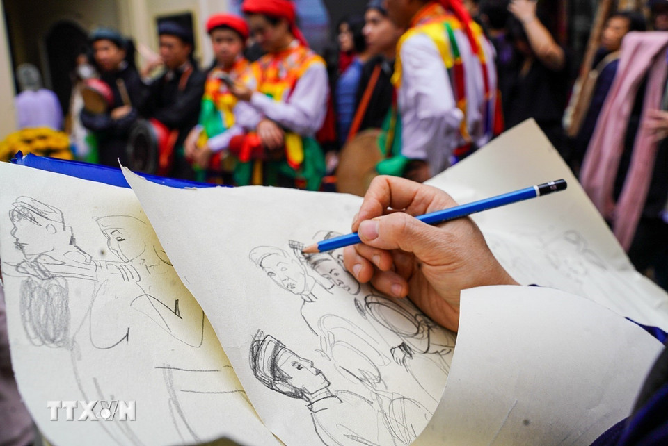 Một họa sỹ tốc ký nhanh những trang phục cổ phục Việt. (Ảnh: Khánh Hòa/TTXVN)