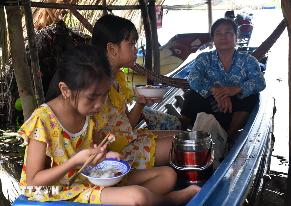 Bữa cơm trưa của học sinh đi học bằng xuồng ghe đến trường. (Ảnh: Tuấn Phi/TTXVN)