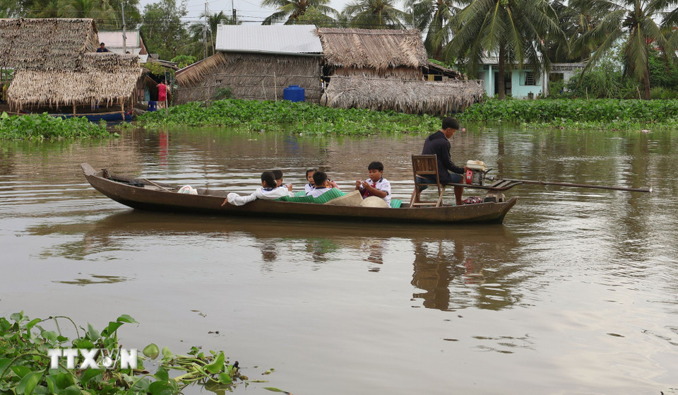 Học sinh đi học bằng xuồng ghe tại xã Mỹ Phước (thành phố Cần Thơ). (Ảnh: Tuấn Phi/TTXVN)