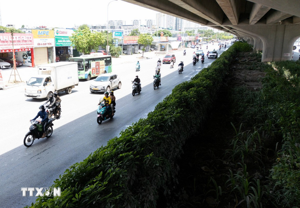 Các phương tiện xe mô tô, gắn máy đi nép vào phần đường có bóng mát để tránh nắng trên đường Nguyễn Xiển, Hà Nội. (Ảnh: Lê Đông/TTXVN)