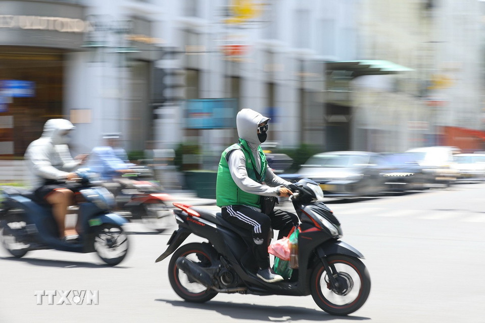Tài xế giao hàng công nghệ mưu sinh tại Hà Nội giữa cái nắng hơn 40 độ. (Ảnh: Lê Đông/TTXVN)