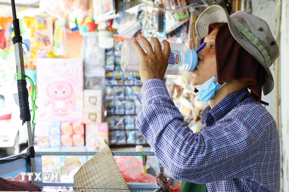 Nắng nóng gay gắt, nhiều lao động tại Hà Nội phải tìm cách thích nghi để tiếp tục mưu sinh. (Ảnh: Lê Đông/TTXVN)