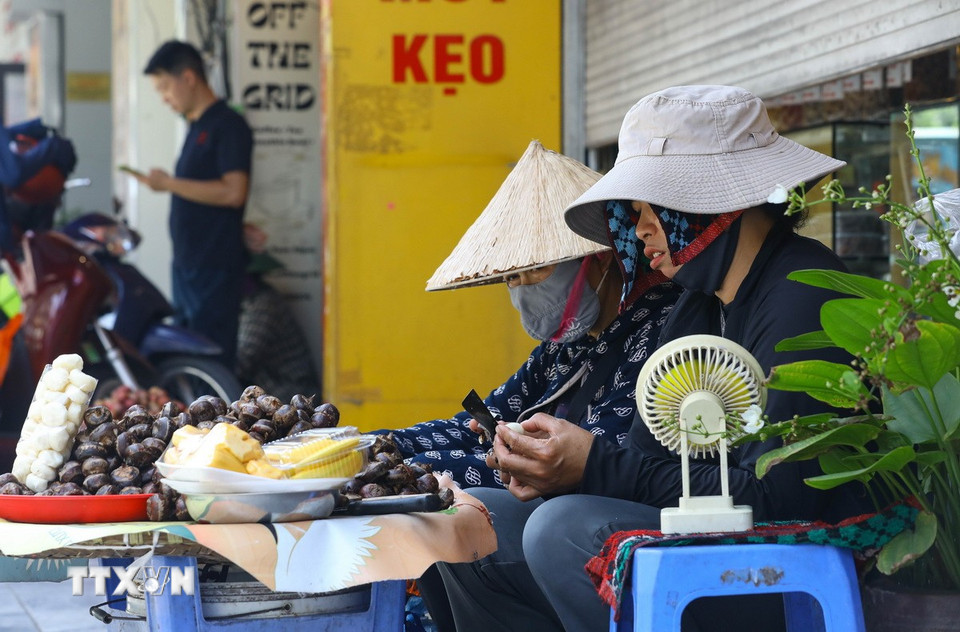 Những người kinh doanh tự do tại Hà Nội tìm mọi cách giải nhiệt giữa thời tiết nắng nóng cực đoan. (Ảnh: Lê Đông/TTXVN)